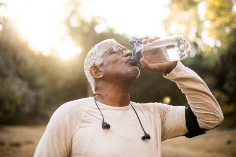 older man running drinking water